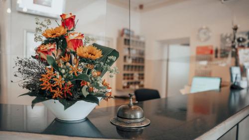 eine Vase voller Blumen auf einer Theke mit Glocke in der Unterkunft Avantgarde Hotel in Hattingen