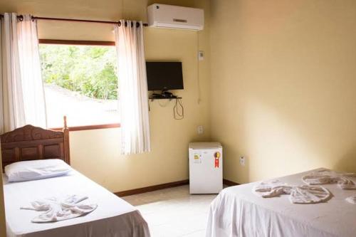 a room with two beds and a window and a television at Pousada Nativa in Paraty