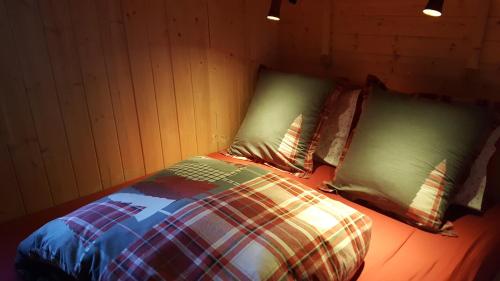 a bed in a room with two pillows at Ma Roulotte sous les Chênes "la passionnée" in Raon-aux-Bois
