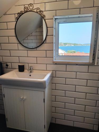 ein Bad mit einem Waschbecken, einem Spiegel und einem Fenster in der Unterkunft Apartman Luka in Viganj