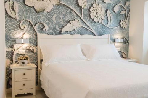 una camera con letto bianco e carta da parati blu e bianca di Marinelli Apartments - La Madonnina a Osimo
