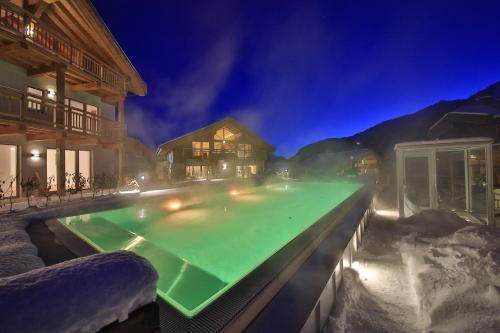 a swimming pool at night with snow on the ground at Mountains Hotel in Seefeld in Tirol