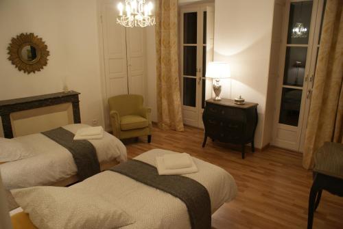 サン・ジャン・ド・ローヌにあるLe Relais des Négociantsのベッドルーム1室(ベッド2台、椅子、シャンデリア付)