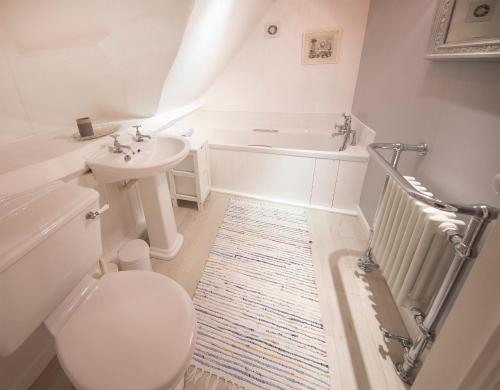 een badkamer met een toilet, een wastafel en een bad bij The Burrow in Chideock