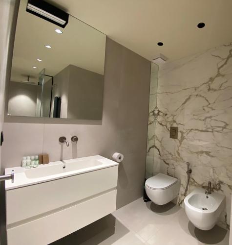 a bathroom with a sink and a toilet and a mirror at SETTANNI Sea Suites in Polignano a Mare