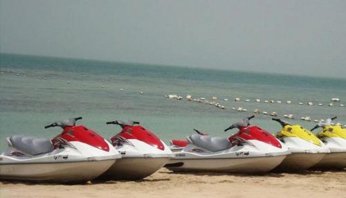 a row of motor scooters parked on the beach at Seashell Julai'a Hotel & Resort Family resort in Al Qulay‘ah