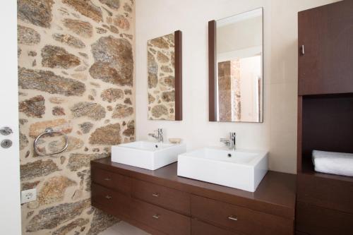 baño con 2 lavabos y pared de piedra en Quinta da Devesa, en Valença