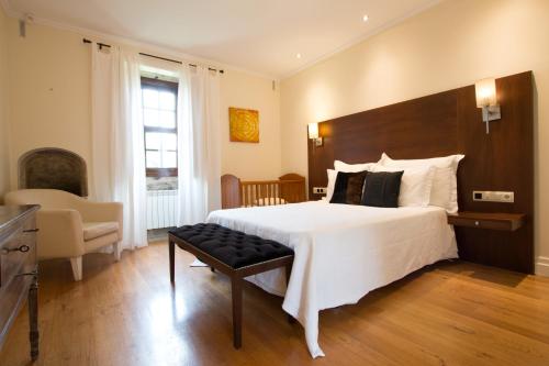 Un dormitorio con una gran cama blanca y una silla. en Quinta da Devesa, en Valença