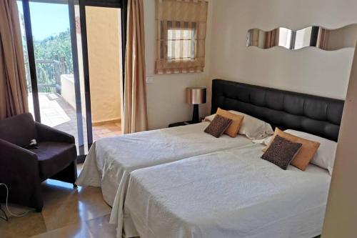 een slaapkamer met een groot bed en een stoel bij Khios 401 Coto Real, La Duquesa, Manilva in San Luis de Sabinillas