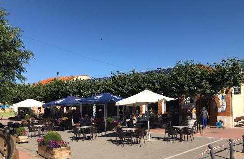 a patio with tables and chairs and umbrellas at La casa de Jesús Llandres in Husillos