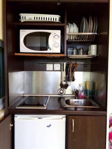 a kitchen with a sink and a microwave at CoCoKreyol - Ti CARAYOU in Les Trois-Îlets