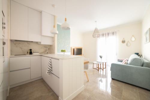 a kitchen and living room with white cabinets and a couch at Apartamentos San Francisco - Centrico in Mota del Cuervo