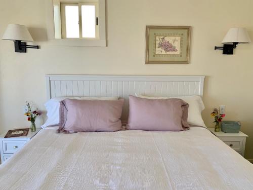 a white bed with two purple pillows on it at Annie's Place Bed & Breakfast in Boulder Town