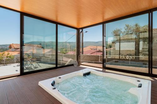 a hot tub in a room with large windows at Casa de Lagarinhos JACUZZI SPA JOGOS GYM - SERRA DA ESTRELA - SEIA - GOUVEIA in Gouveia