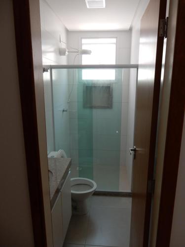 a bathroom with a toilet and a glass shower at Apto 501 O conforto de sua casa na praia do morro in Guarapari