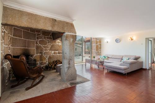 uma sala de estar com uma lareira de pedra e um sof em Casa de Lagarinhos JACUZZI SPA JOGOS GYM - SERRA DA ESTRELA - SEIA - GOUVEIA em Gouveia