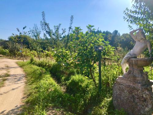 a statue of a man sitting on a rock next to a dirt road at Chambre de la tour - Quinta da Prelada Simão in Celorico de Basto