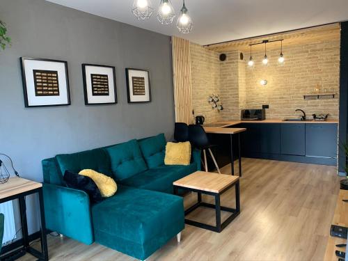 a living room with a blue couch and a kitchen at Tarnovia Loft Apartment in Tarnowo Podgórne