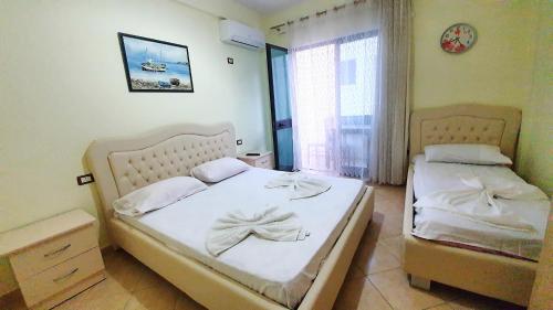 a bedroom with two beds with white sheets and a window at Vila Vera in Durrës