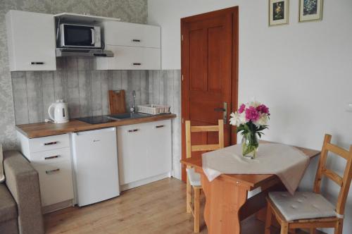 a kitchen with a table with a vase of flowers on it at amel orawa in Podwilk