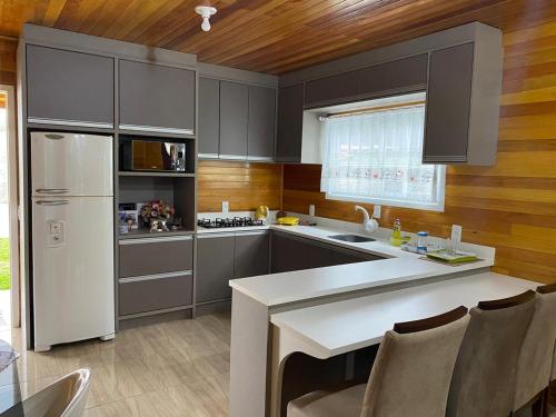 cocina con armarios grises y nevera blanca en Casas de Hospedagem Mendes, en Urubici