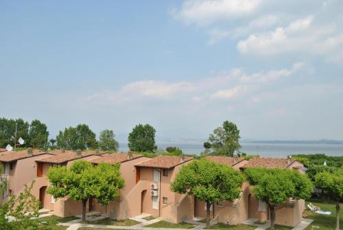 eine Reihe von Häusern mit Bäumen davor in der Unterkunft Ohana Apartments Camping Tiglio in Sirmione