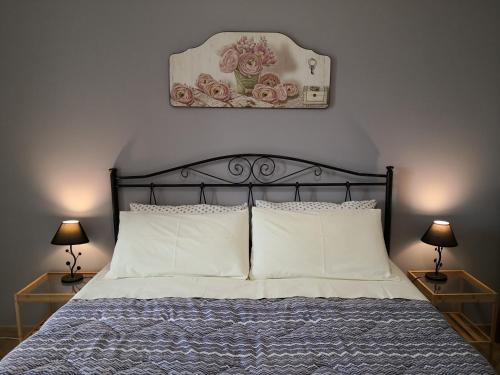 ein Bett mit weißen Kissen und einem Bild an der Wand in der Unterkunft B&B Il Papavero Rosso in Corigliano dʼOtranto