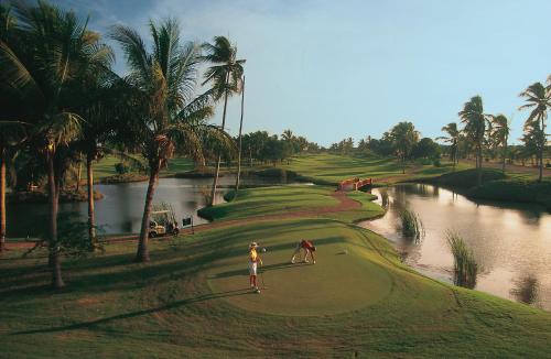 two people on a golf course next to a river at Grand Isla Navidad Golf & Spa Resort with Marina in Barra de Navidad
