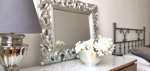 a mirror and a vase with flowers on a table at Birbiciù in Pantelleria