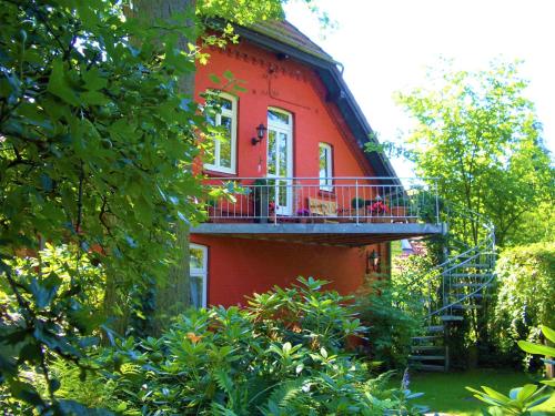 a red building with a balcony on the side of it at Ferienhaus Eichhof, Garlstorf - Lüneburger Heide in Garlstorf