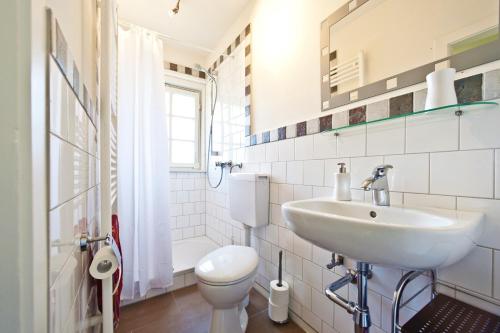 een witte badkamer met een wastafel en een toilet bij FeWo Katharina (Teestube Undeloh) Lüneburger Heide in Undeloh