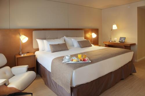 a hotel room with a large bed with a tray of food on it at Dazzler by Wyndham Montevideo in Montevideo