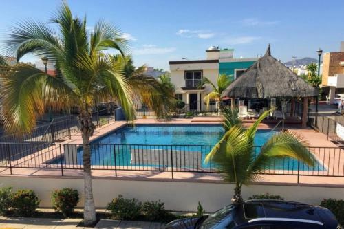 una piscina con palme di fronte a un edificio di Casa vacacional a 5 min de la playa, 12 o más personas a Mazatlán