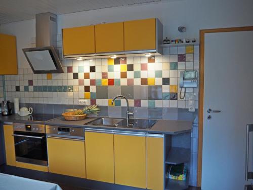 una cocina con armarios amarillos y fregadero en Ferienhaus-stadtkyll-eifel Beim Förster mit zwei Schlafzimmern, en Stadtkyll