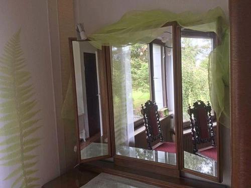 a mirror in a room with two windows at Ferienhaus-stadtkyll-eifel Beim Förster mit zwei Schlafzimmern in Stadtkyll