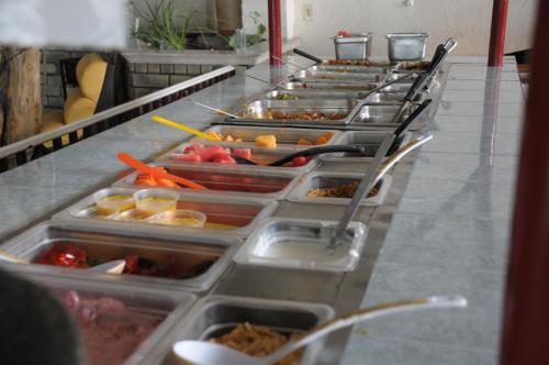 a buffet line of trays of food in a restaurant at Hotel Raldos Inn in Salamanca