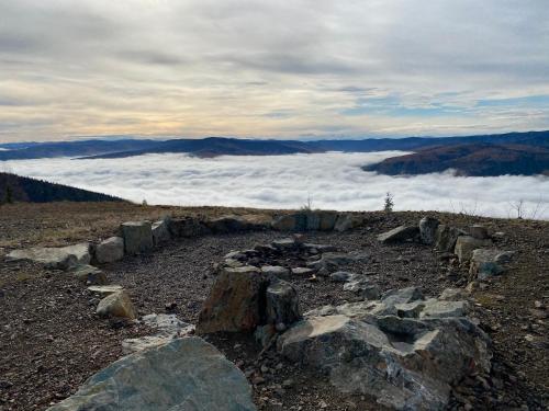 a pile of rocks on top of a mountain with clouds at Dawson Lodge in Dawson City