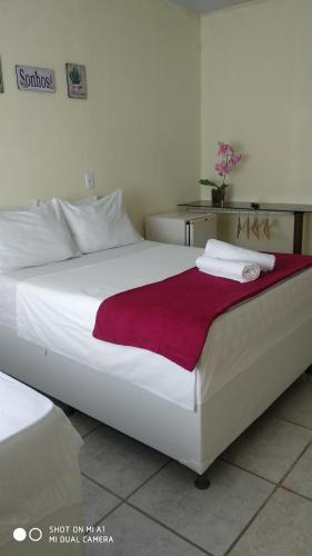 a bedroom with a large white bed with a red blanket at Pousada Nordestina in Recife