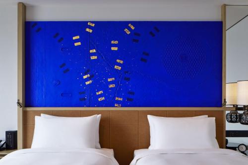 two beds in a room with a large blue painting on the wall at Hyatt Centric Kanazawa in Kanazawa