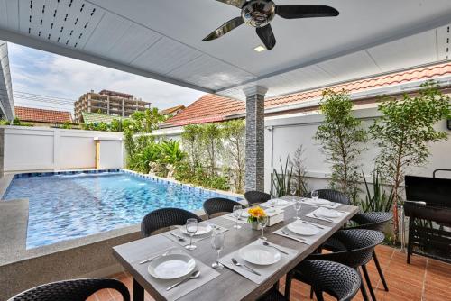 a dining room with a table and a swimming pool at Gala Villa Pattaya in Pattaya South