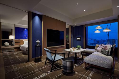 a living room with a couch and a table and a bed at Hyatt Centric Kanazawa in Kanazawa