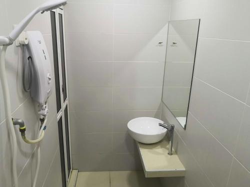 uma casa de banho branca com um WC e um espelho. em Tropika Garden Hotel em Johor Bahru