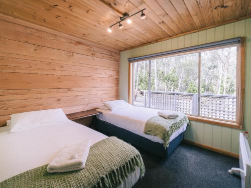 two beds in a room with a window at The Pier House in Lunawanna