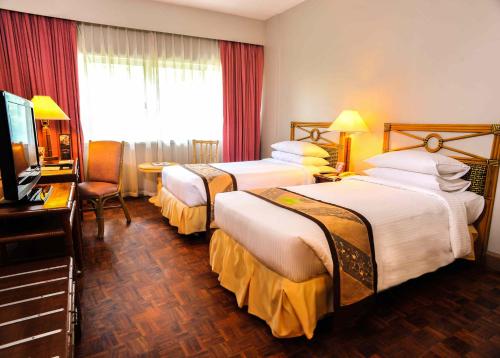 ダバオシティにあるWaterfront Insular Hotel Davaoのベッド2台とテレビが備わるホテルルームです。