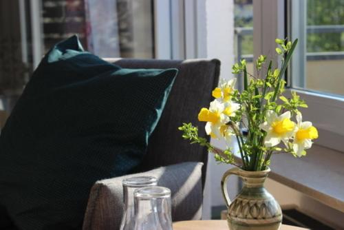 a vase of flowers on a table with a chair at Haus Seefrieden in Uhldingen-Mühlhofen