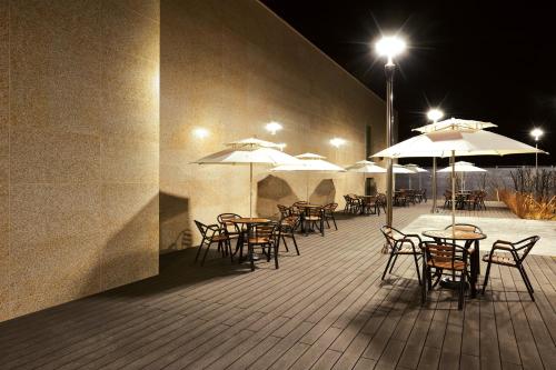 a patio with tables and chairs with umbrellas at night at Jeongseon Intoraon Hotel in Jeongseon