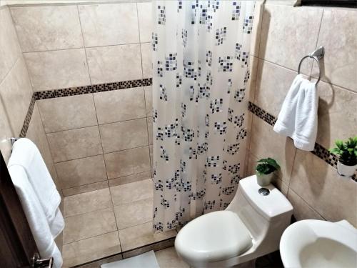 y baño con aseo y cortina de ducha. en Kubo Apartment Private 2 Bedrooms 5 mins SJO Airport with AC, en Alajuela