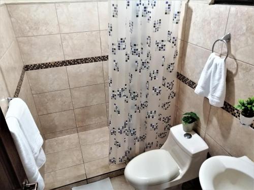 a bathroom with a toilet and a shower curtain at Kubo Apartment Private 2 Bedrooms 5 mins SJO Airport with AC in Alajuela