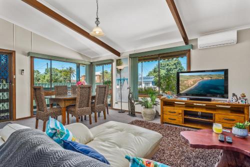 a living room with a couch and a tv at Footprints in the Sand, Silver Sands Beach House in Aldinga Beach