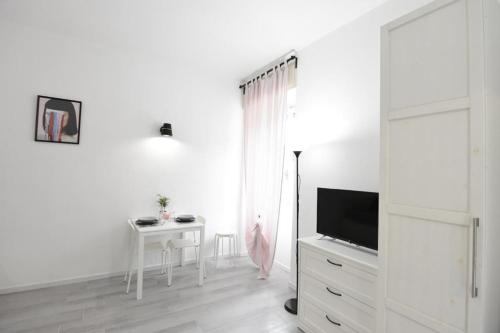 a white living room with a table and a television at La Casa di Oreno in Vimercate